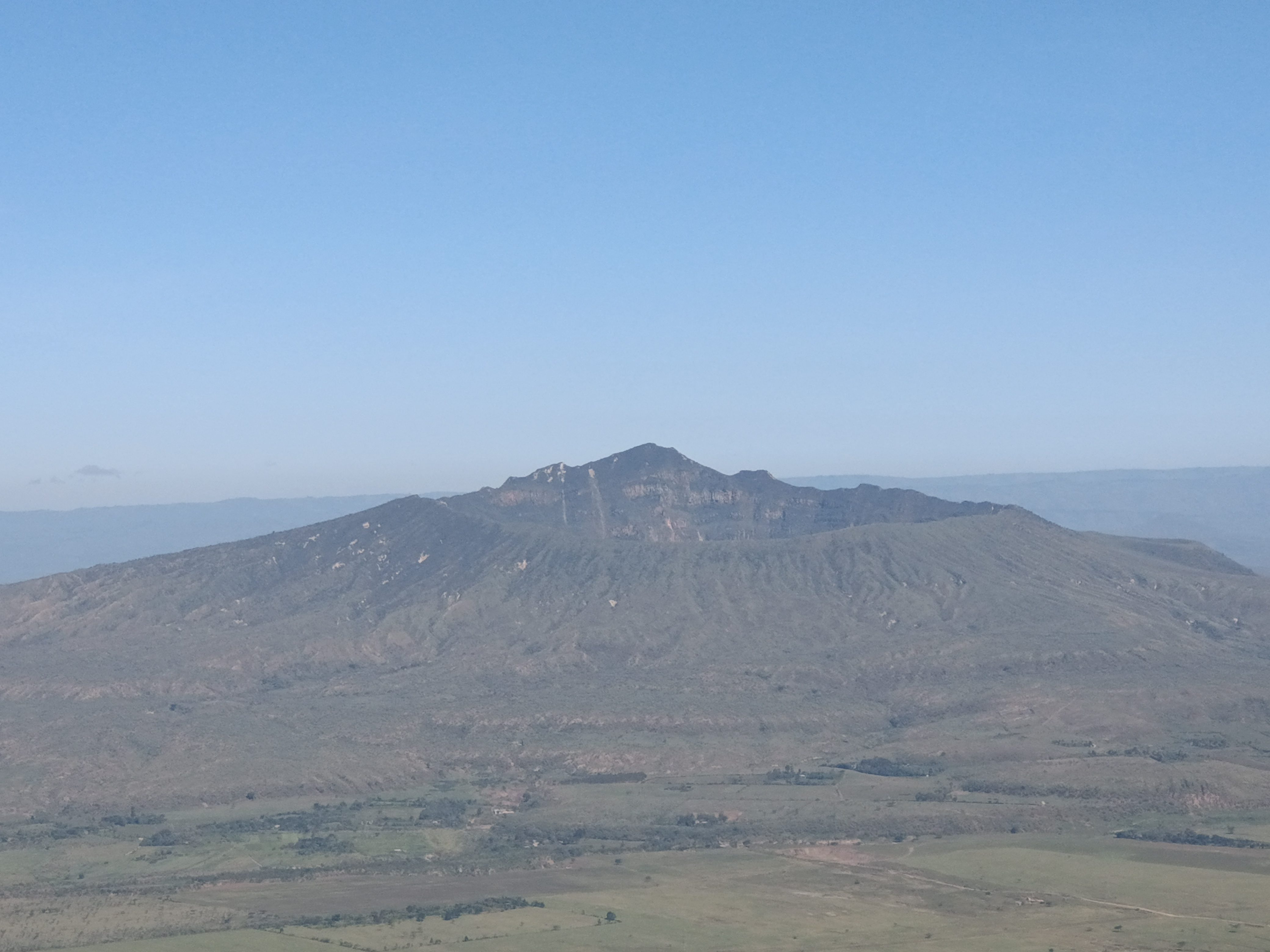 Aerial view of tandem paragliding above green hills