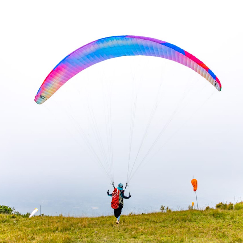 Pilot launching a colorful paraglider wing at Mawingu Camp